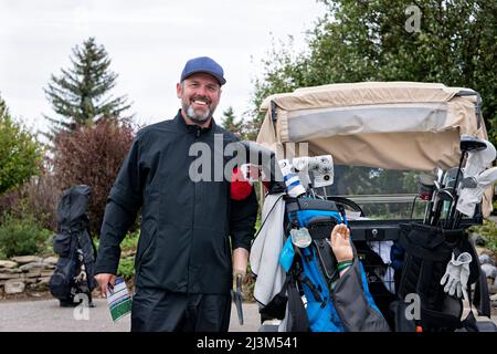 Golfer with arm prothesis standing beside a golf cart at a golf course; Okotoks, Alberta, Canada Stock Photo