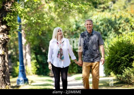 Mature couple holding hands while walking outdoors on a park trail; Edmonton, Alberta, Canada Stock Photo