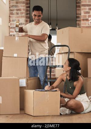 We are most alive when were in love. Shot of a young couple packing up to move in a room at home. Stock Photo