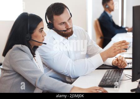 Try doing it like this next time. Shot of two call centre agents working together on a computer in an office. Stock Photo