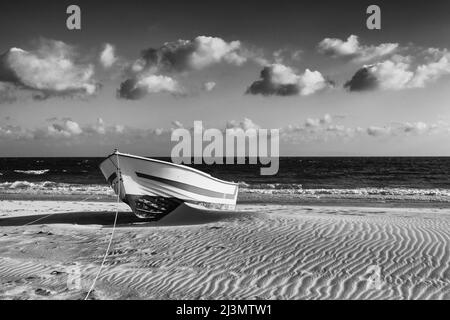 Lonely wooden boat on the beach close to dunes in Bolonia, Andalusia, Spain. This dune is over 30 metres high and 200 metres wide.Black and white phot Stock Photo