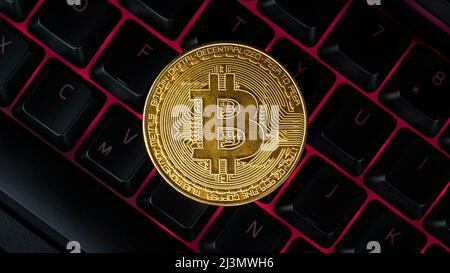 Bitcoin on compuer keyboard in background, symbol of electronic virtual money and mining cryptocurrency concept. Coin crypto currency bitcoin lies on Stock Photo