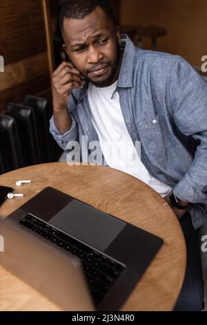 Exhausted tired African American businessman sitting at work desk with closed eyes, falling asleep, overworked young man, unmotivated student sleeping Stock Photo