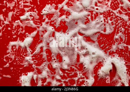 Texture of white soap foam with bubbles abstract red background, Soap, shower gel, shampoo, Face Cream cleansing mousse sample. Stock Photo