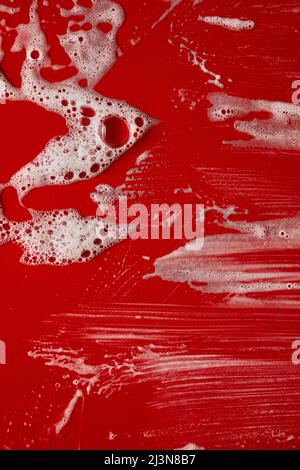 Texture of white soap foam with bubbles abstract red background, Soap, shower gel, shampoo, Face Cream cleansing mousse sample. Stock Photo