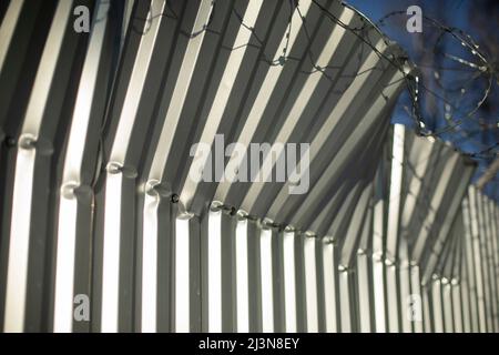 Broken fence. Fence from profile sheet bent. Rumpled iron. Damage to fence. Stock Photo