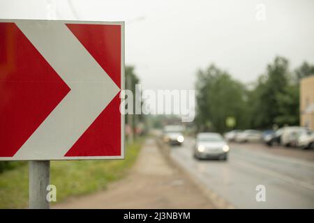 Sharp turn sign on road. Place of sharp bend in road. Red road sign with white arrow. Stock Photo