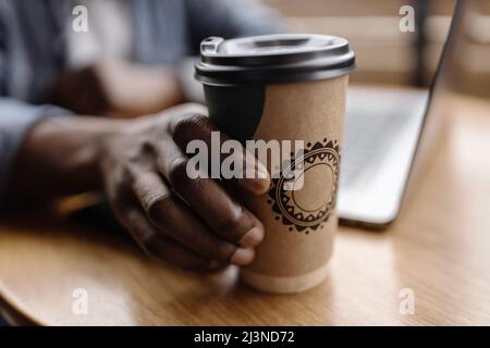 A young businessman leads a virtual meeting online. Nearby there is a glass of invigorating coffee; after the conference, the business man will take a Stock Photo