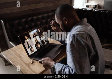 Exhausted tired African American businessman sitting at work desk with closed eyes, falling asleep, overworked young man, unmotivated student sleeping Stock Photo