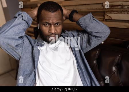 Close-up portrait of serious African American young man having fun talking on cell phone in office. Delighted with good news, has a pleasant funny Stock Photo