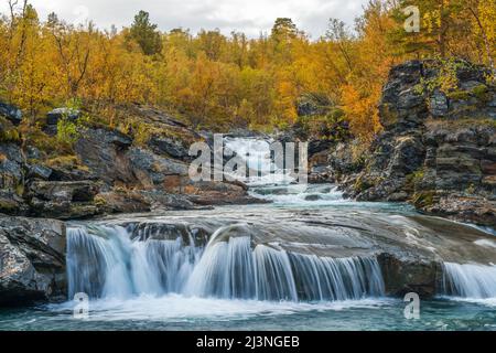 Kårsajokka in autumn season with nice turquoise water and colorfull trees, Abisko, Swedish Lapland, Sweden Stock Photo