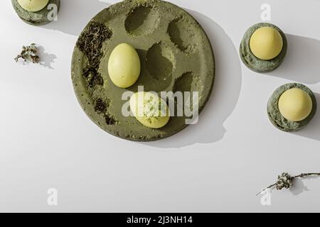 Zero waste Easter concept. Easter eggs coloured with matcha tea in moss green cement tray. Eco friendly lifestyle. Modern and contemporary interior de Stock Photo