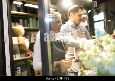 two experienced florists in the refrigerator select flowers for a bouquet Stock Photo
