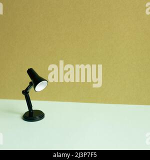Black desk lamp on sky blue desk. khaki wall background Stock Photo