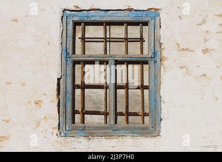 Old building wall and closed wooden window with rust iron grille Stock Photo