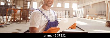 Cheerful male worker holding building architectural plan Stock Photo