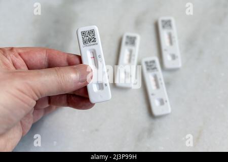 Self- or home-administered rapid lateral flow tests (LFT) for COVID-19 Coronavirus, both positive and negative; hand holding negative result Stock Photo