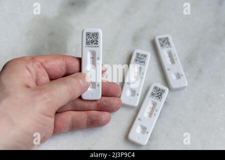 Self- or home-administered rapid lateral flow tests (LFT) for COVID-19 Coronavirus, both positive and negative; hand holding negative result Stock Photo