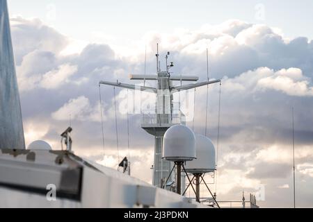 Shipping sea car ferry radar system on boat mast, satellite system with sunset in dramatic sky behind over ocean. Stock Photo