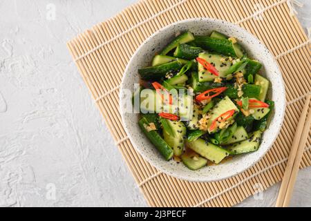 Asian spicy salad Broken Cucumbers with fresh coriander, ginger, pepper chili, black vinegar. Popular Chinese and Vietnam cold appetizer. Top view. Stock Photo