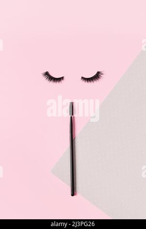 Creative layout with eyelashes and brush mascara. Closed eyes on pastel pink background. Stock Photo