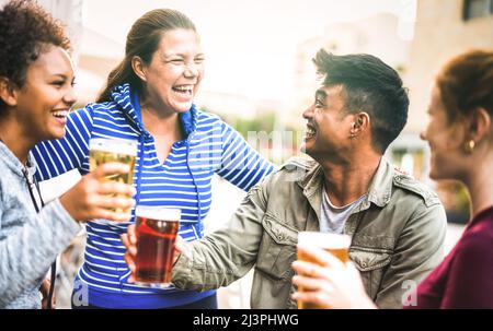 Multicultural friends drinking and toasting beer pints at brewery bar garden out side - Beverage life style concept with men and women having fun Stock Photo