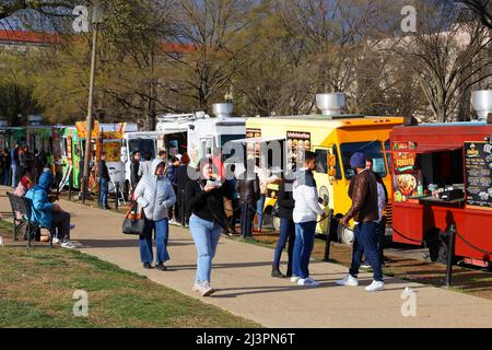 People eating, and buying food from dozens of food trucks lined along the National Mall, 7th St NW, Washington DC. Stock Photo