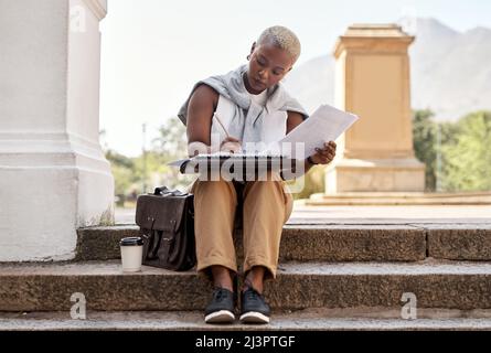 Success is something you need to consistently be planning for. Shot of a young businesswoman going through paperwork while sitting on a staircase Stock Photo