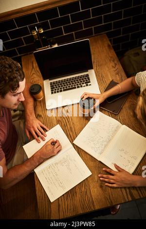 Inspiring each other to study harder. High angle shot of two unidentifiable students having a study session at a cafe table. Stock Photo