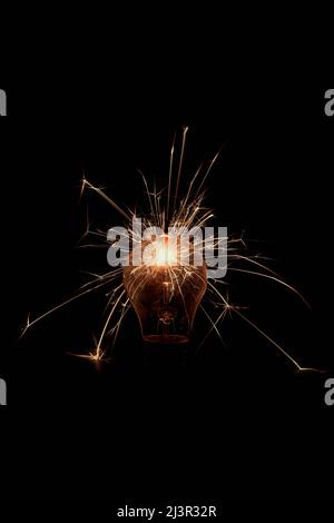 Incandescent lamp with sparks on a black background. Stock Photo
