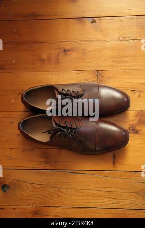 Elegant and Classic Brown Leather Dress Shoes on a Rustic Wood Floor Stock Photo