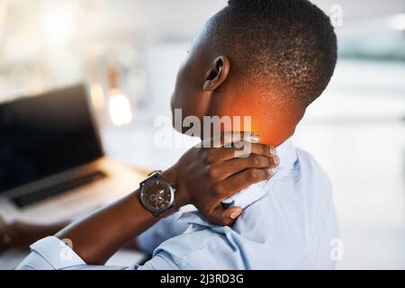 I think its time I called it a day. Shot of a young unrecognizable businessman suffering from neck pain while trying to work in the office. Stock Photo