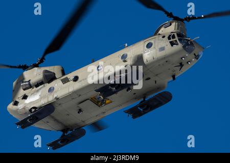 An Alaska Army National Guard CH-47 Chinook helicopter, operated by Army aircrew assigned to B Company, 2-211th General Support Aviation Battalion, passes over Geronimo Drop Zone while supporting airborne training at Joint Base Elmendorf-Richardson, Alaska, April 7, 2022. Special warfare Airmen from Detachment 1, 3rd Air Support Operations Squadron and Detachment 3, 1st Combat Weather Squadron, conducted the training to demonstrate airborne and mission-readiness skills in an arctic environment. (U.S. Air Force photo by Alejandro Peña) Stock Photo