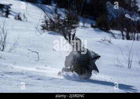 A U.S. Air Force tactical air control party (TACP) specialist assigned to Detachment 1, 3rd Air Support Operations Squadron, lands after jumping from a U.S. Army CH-47 Chinook helicopter assigned to B Company, 2-211th General Support Aviation Battalion, Alaska Army National Guard, at Joint Base Elmendorf-Richardson, Alaska, April 7, 2022. The 3rd ASOS completed the helicopter jump on Geronimo Drop Zone, maximizing total-force training to demonstrate short-notice mission readiness in an arctic environment. (U.S. Air Force Photo by Airman 1st Class Julia Lebens) Stock Photo