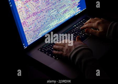 Freelance web developer working at night, programming the web with javascript like a hacker. Close-up hand and computer Stock Photo