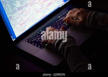 Freelance web developer working at night, programming the web with javascript like a hacker. Close-up hand and computer Stock Photo