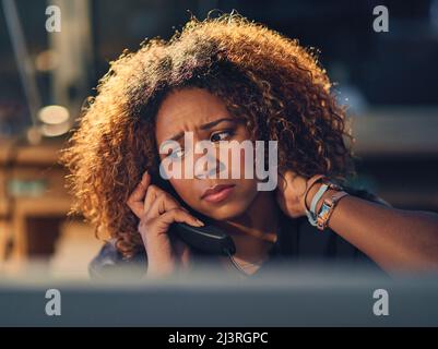 Thats not what I wanted to hear. Shot of a young businesswoman making a stressful phone call during a late night at work. Stock Photo