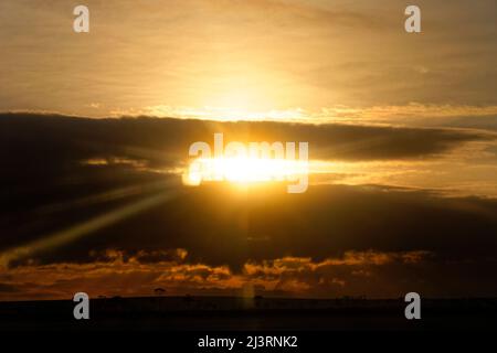 Setting sun behind dark clouds Stock Photo