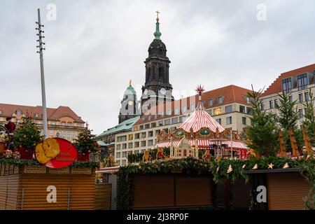 587th Dresdner Striezelmarkt small wooden houses at the famous Christmas market in Saxony. The church tower and the town hall tower is visible. Stock Photo