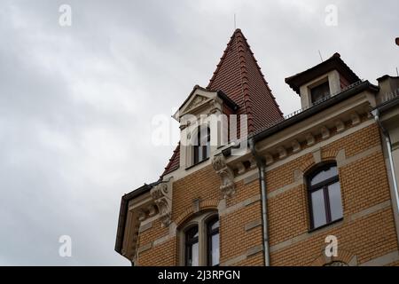 Old building with ancient architecture and a clinker facade in front of an overcast sky. Beautiful yellow house with a lot of details. Looking up. Stock Photo