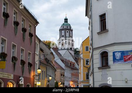 Church of Our Lady in the inner city behind small houses. The old town with shining street lights in the evening. A street view into a narrow alley. Stock Photo