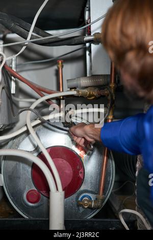 He knows those pipes like the back of his hands. Cropped shot of a handyman repairing a pipe on a water heater. Stock Photo