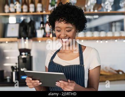 Taking advantage of technological tools to boost sales. Shot of a young woman using a digital tablet while working in a cafe. Stock Photo
