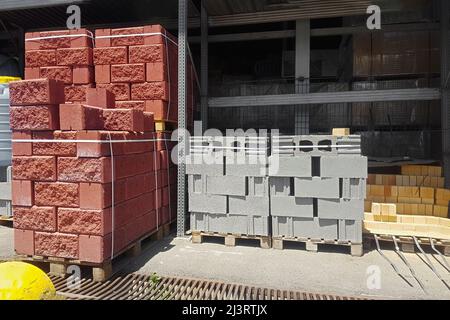 Hollow red and gray bricks stacked on pallets for sale. Stock Photo