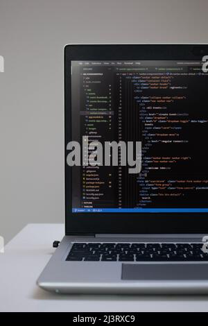 Opened laptop with code on the screen on the table Stock Photo
