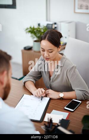 Please read through this. Shot of a businesswoman reading through a contract with a customer. Stock Photo