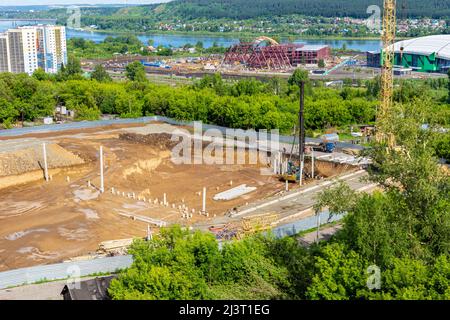 mass construction on the territory of the city, near the river bank, in the foundation pit there is a pile driver or a pile driver that has driven sev Stock Photo