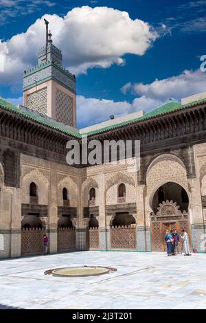 Fes, Morocco.  Medersa Bou Inania.  Tourists with Guide in the interior Courtyard. Stock Photo