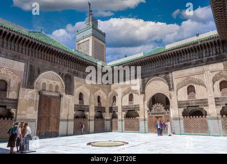 Fes, Morocco.  Medersa Bou Inania.  Tourists with Guide in the interior Courtyard. Stock Photo