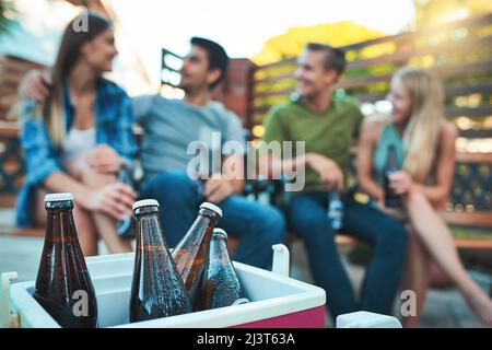 They dont call it a chill out session for nothing. Shot of bottled beers chilling in a cooler box with a group of friends hanging out in the Stock Photo